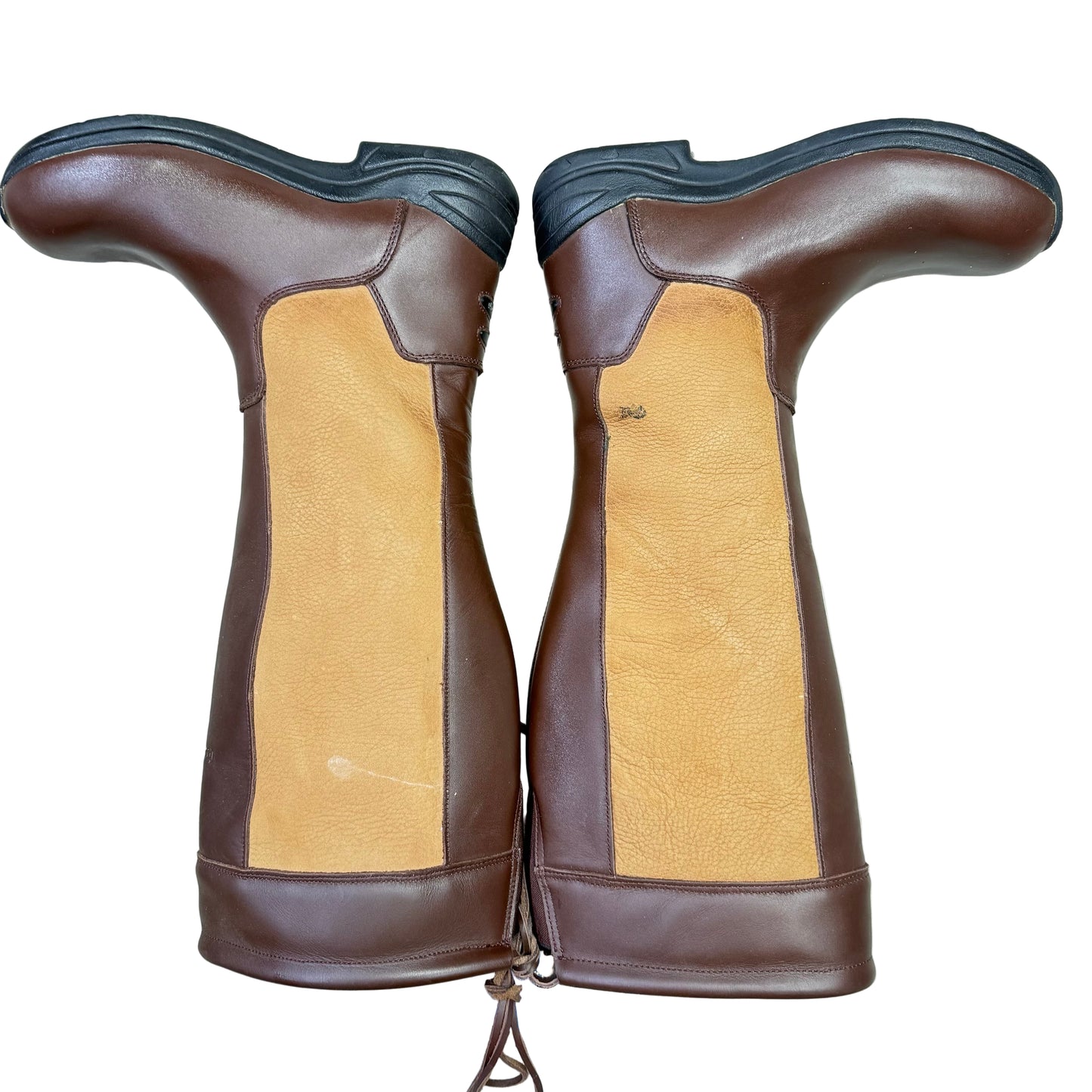 Pair of brown and tan leather boots on a light gray floor.